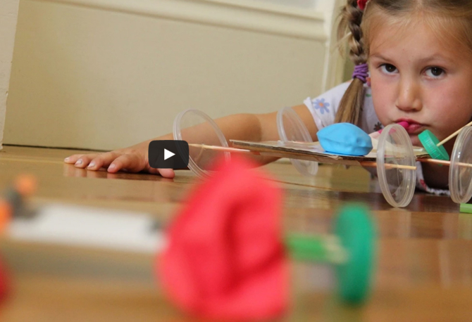 A screenshot showing a girl with a balloon car