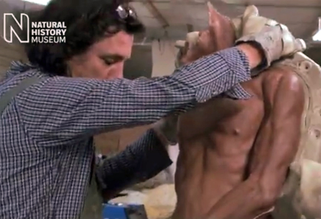A screenshot showing a man handling a mannequin