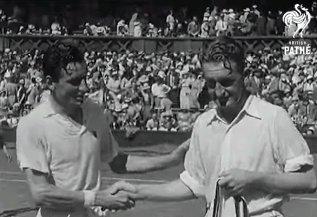 A black and white screenshot showing two men shaking hands