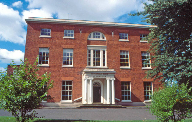 A large red brick house with a portico and a sign reading Broadfield House Glass Museum