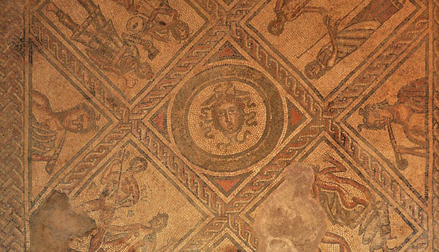 A Roman mosaic with a man's head in the centre surrounded by figures from other mythological scenes