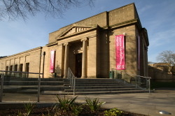 An image of a large building with Neoclassical columns and red banners