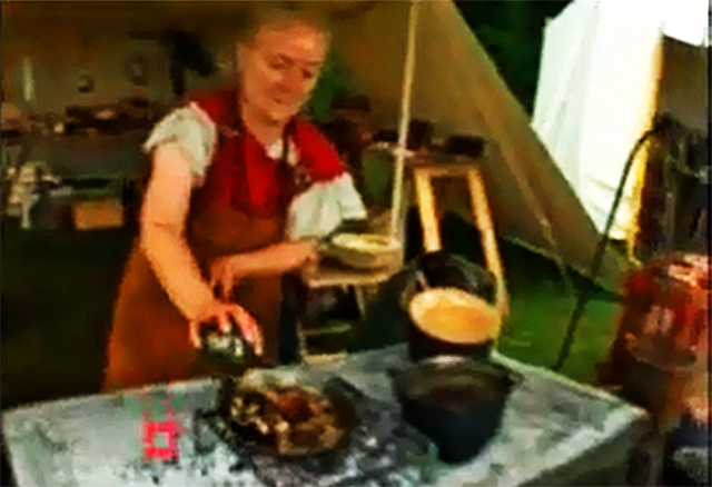 Shows a woman dressed as a Roman preparing a meal