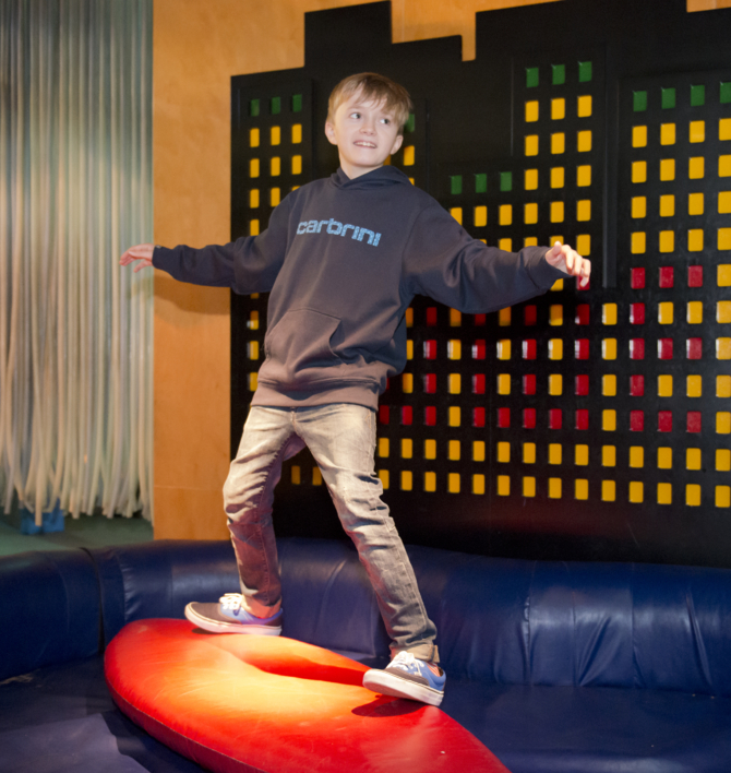 Boy rides a surfboard in Our Global Garden at Eureka!