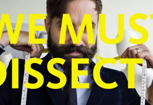 A screenshot showing yellow letters in front of a mand with a beard. 