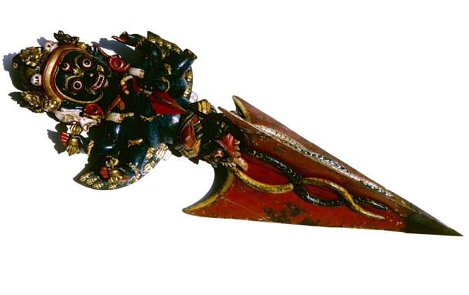 Red, blue, white and gold three sided carved dagger with grinning monsters and deity faces. 